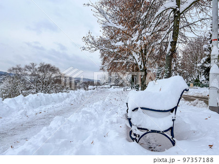 Snow-covered bench overlooking the embankment and the city under lots of snow in the morning in natural light 97357188