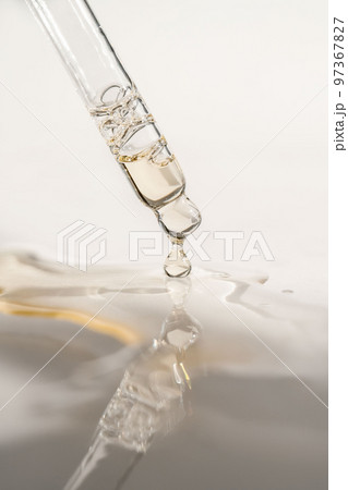 A drop of cosmetic oil falls from the pipette 97367827