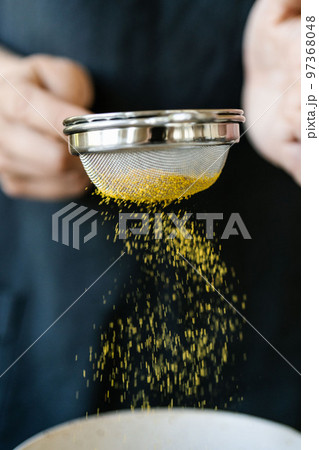 The girl sifts turmeric into a bowl. The girl sifts turmeric into a bowl. 97368048