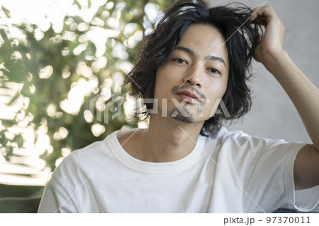 髪を掻き上げる白いTシャツを着た若い男性　 97370011