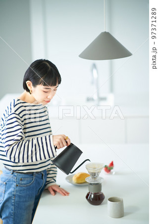 部屋でコーヒーを淹れる若い女性 部屋でコーヒーを淹れる若い女性 97371289