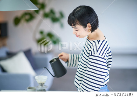 部屋でコーヒーを淹れる若い女性 部屋でコーヒーを淹れる若い女性 97371297