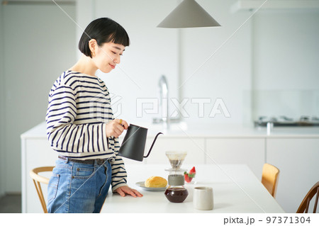 部屋でコーヒーを淹れる若い女性 部屋でコーヒーを淹れる若い女性 97371304