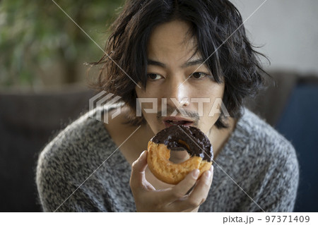 ドーナツを食べる若い男性 97371409