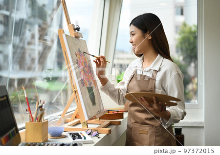 Beautiful asian woman painting picture with acrylic paints on canvas, enjoying creative leisure activities. Art and leisure activity concept 97372015