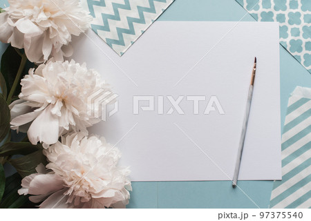 Gogreous white peonies flowers and empty tag on blue background. Flat lay. Top view with copy space and a brush for watecolor text. Gogreous white peonies flowers and empty tag on blue background. Flat lay. Top view with copy space and a brush for watecolor text. 97375540