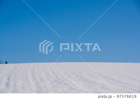 青空と雪が積もった冬の畑 97376619