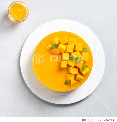Delicious glazed mango no baked cheese cake with fresh diced mango pulp topping on bright table background. Delicious glazed mango no baked cheese cake with fresh diced mango pulp topping on bright table background. 97378243