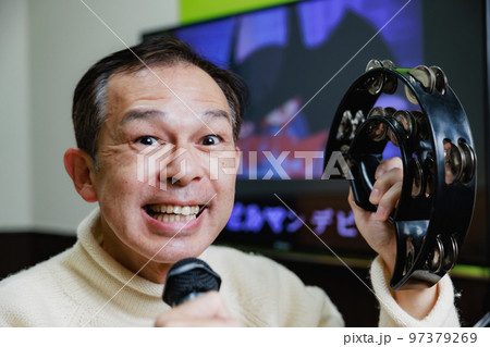 一人カラオケでタンバリンを持って盛り上がっている中年男性 一人カラオケでタンバリンを持って盛り上がっている中年男性 97379269