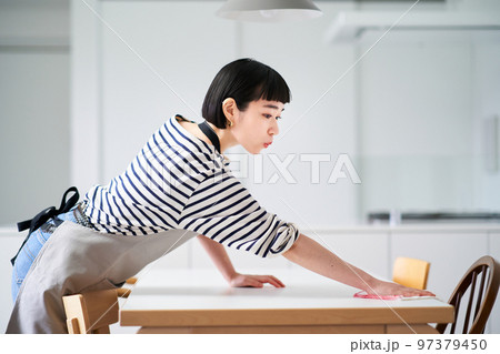 ダイニングテーブルを拭く若い女性 97379450
