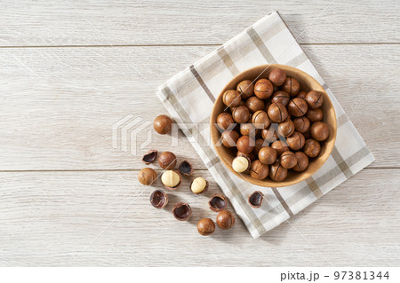 Macadamia in wooden bowl on white table with copy space. Top view Macadamia in wooden bowl on white table with copy space. Top view 97381344