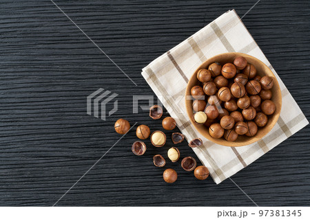 Macadamia in wooden bowl on black table with copy space. Top view Macadamia in wooden bowl on black table with copy space. Top view 97381345