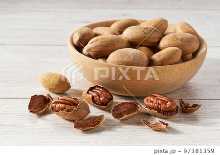 Pecan in wooden bowl on white table. 97381359