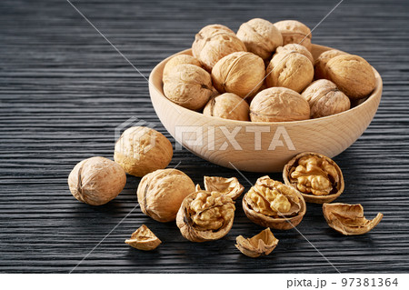 walnuts in wooden bowl on black table. walnuts in wooden bowl on black table. 97381364