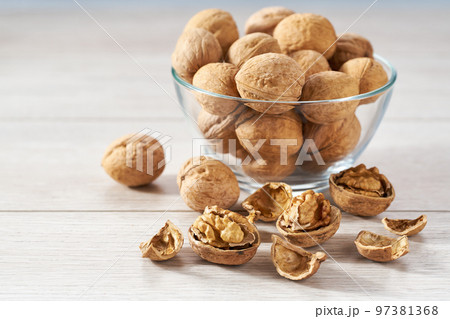 organic walnuts in a glass plate and scattered on a white kitchen table, selective focus. 97381368