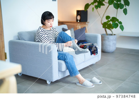 部屋で靴下を履く若い女性 97384748