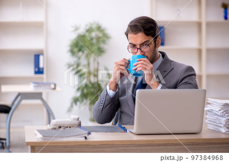 Young male employee drinking coffee during break 97384968