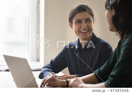 Happy young Indian employee woman talking to colleague 97385936