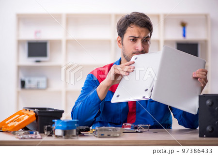 Young male repairman repairing computer 97386433