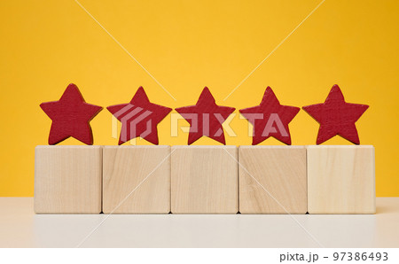 Five stars on wooden cubes, yellow background. Service evaluation concept 97386493