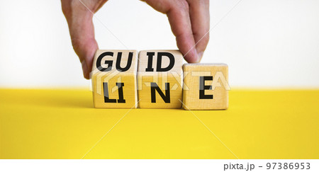 Guideline symbol. Concept word Guideline on wooden blocks. Businessman hand changes words Guide on Line. Beautiful yellow table white background. Business and guideline concept. Copy space. 97386953