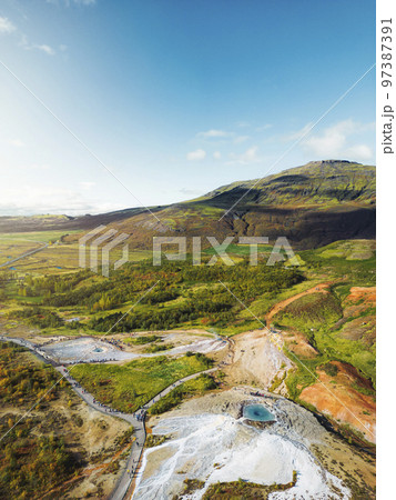 Tourist exploring area of Great geyser in Iceland - Vertical aerial photo 97387391