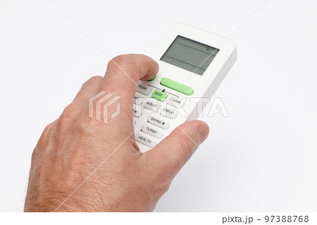 Man's hand using remote controler. Hand holding remote and adjusting temperature of air conditioner mounted on a white wall. 97388768