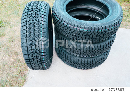 Four new snow tires on the backyard. A set of studded winter car tires. Black Rubber Tire. Vehicle Tires. Four new snow tires on the backyard. A set of studded winter car tires. Black Rubber Tire. Vehicle Tires. 97388834