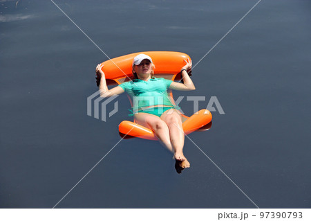Modern woman in swimsuit swaying in water hammock enjoying summer holidays Modern woman in swimsuit swaying in water hammock enjoying summer holidays 97390793
