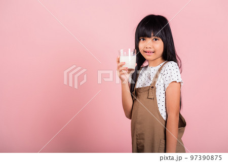 Asian little kid 10 years old smile hold milk glass drink white milk at studio shot isolated on pink background, Happy child girl daily life health care Medicine food Asian little kid 10 years old smile hold milk glass drink white milk at studio shot isolated on pink background, Happy child girl daily life health care Medicine food 97390875