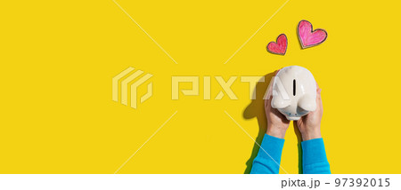 Person holding piggy bank with hearts Person holding piggy bank with hearts 97392015