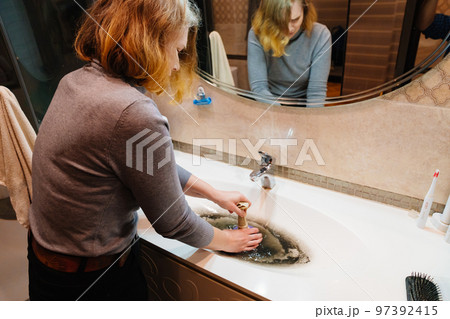 women with plunger and dirty sink with the clog in the pipe. women with plunger and dirty sink with the clog in the pipe. 97392415