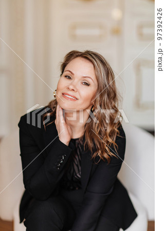 an attractive, feminine and confident woman in a black suit.  97392426