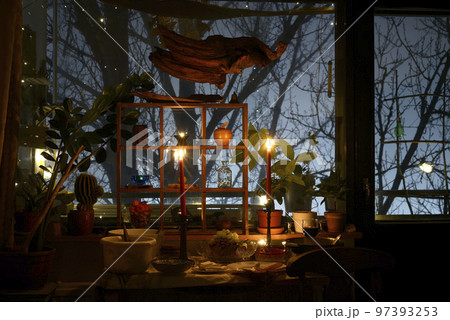 mystical candle-lit room and trees in foggy twilight outside the window 97393253