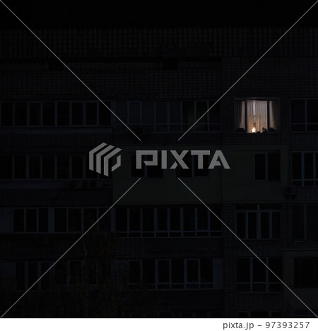 Light in one window in apartment multistorey building during the rolling blackout of electricity in a residential area of Kyiv after russian shelling. 97393257