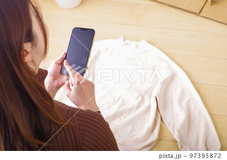 スマホでフリマ出品をする若い女性 97395872