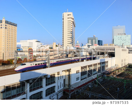 青空を背景に駅を発車する東北新幹線E2系 97397535