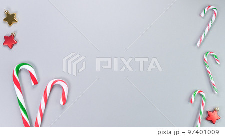 Christmas candy cane, golden and red stars, small and big candies on grey background. Christmas composition. Top view, flat lay Christmas candy cane, golden and red stars, small and big candies on grey background. Christmas composition. Top view, flat lay 97401009