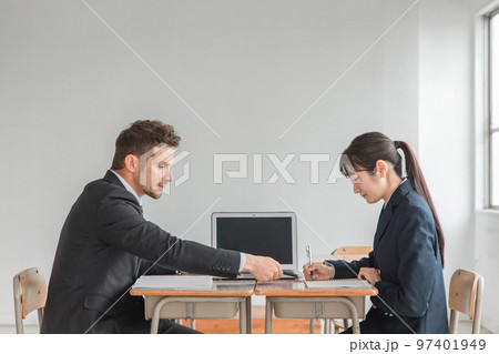 学校で二者面談・進路相談・生徒指導を行う先生・教師と真剣にメモをとるアジア人の中学生・高校生 97401949