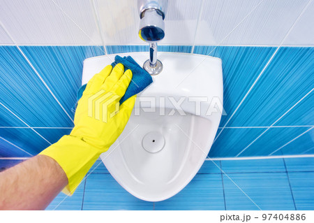 Man wipes man's pissuiar with rag in men's toilet. Gloved hand with close-up rag. Clean and shiny 97404886
