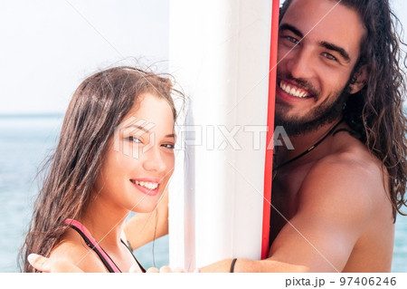 Woman man sea sup. Close up portrait of beautiful young caucasian woman with black hair and freckles looking at camera and smiling. Cute woman portrait in a pink bikini posing on sup board in the sea 97406246