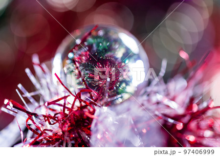 Close-up of Christmas decorations on a tree through lensball sphere Close-up of Christmas decorations on a tree through lensball sphere 97406999