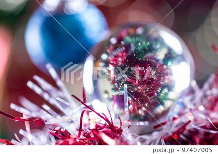 Close-up of Christmas decorations on a tree through lensball sphere Close-up of Christmas decorations on a tree through lensball sphere 97407005