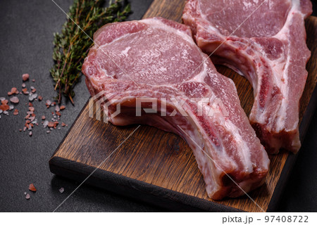Fresh raw pork meat on the ribs with spices and herbs on a wooden cutting board 97408722