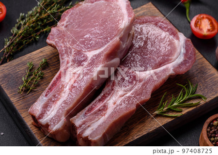 Fresh raw pork meat on the ribs with spices and herbs on a wooden cutting board Fresh raw pork meat on the ribs with spices and herbs on a wooden cutting board 97408725