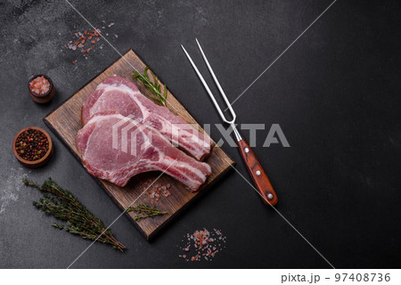 Fresh raw pork meat on the ribs with spices and herbs on a wooden cutting board 97408736