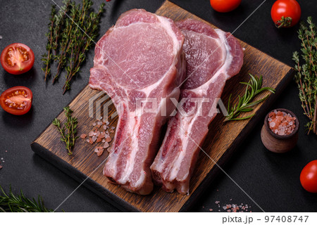 Fresh raw pork meat on the ribs with spices and herbs on a wooden cutting board 97408747