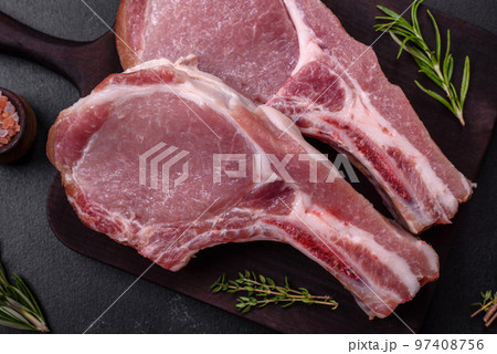 Fresh raw pork meat on the ribs with spices and herbs on a wooden cutting board 97408756