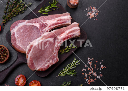Fresh raw pork meat on the ribs with spices and herbs on a wooden cutting board 97408771