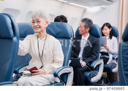 機内エンターテイメントを楽しむ高齢の女性 97409665